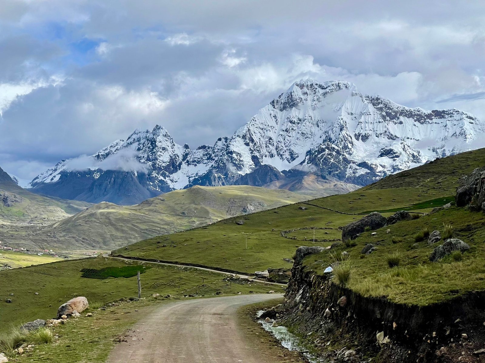 Expert Peru trip planning for the Amazon, Cusco, and Lima, featuring a snow-capped mountain peak and winding road in the Peruvian Andes.