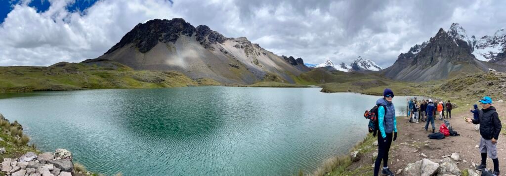 A panoramic view of the turquoise glacial lakes of Ausangate showing groups of tourists on a day trip, illustrating why a rushed itinerary is a "travel checklist error".