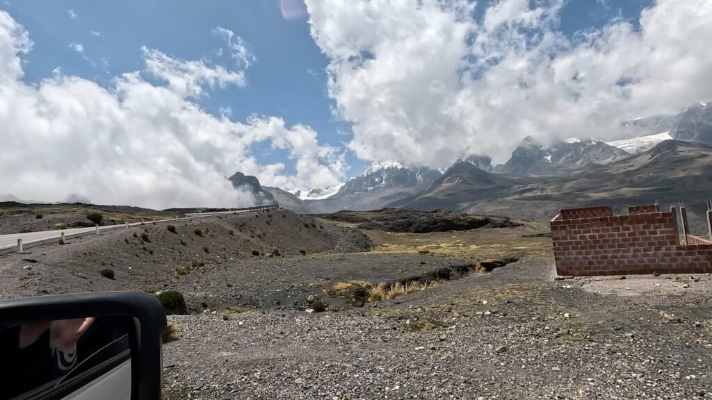 The 30C Interoceanic Highway snaking through the Abra Pirhuayani pass, with steep, rocky mountain walls disappearing into a low-hanging cloud at 4,725 meters.