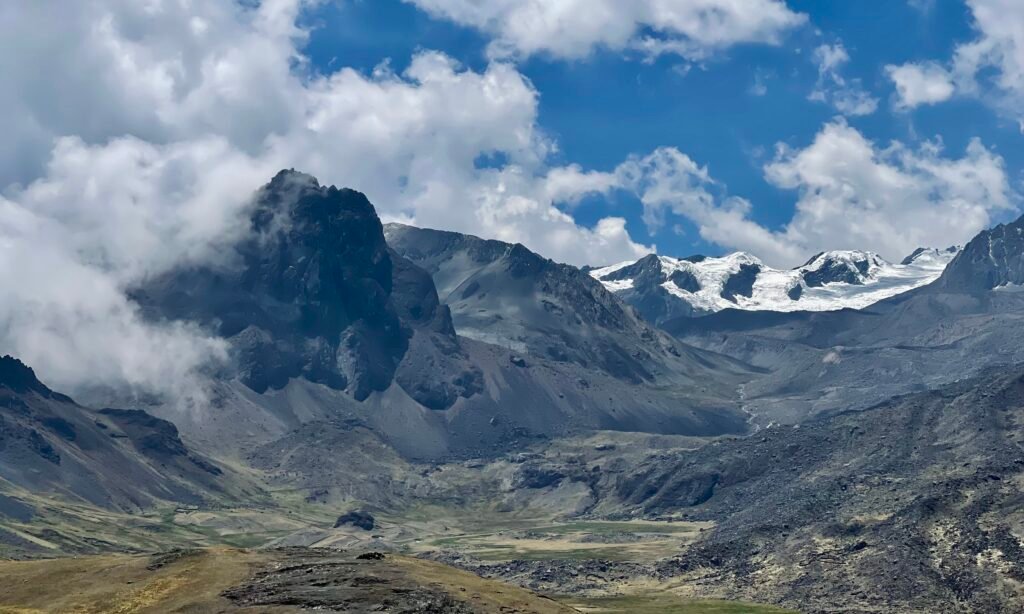 A high-altitude view of the 30C highway cutting through a desolate landscape of grey volcanic rock and brown tundra at the Abra Pirhuayani pass in the Peruvian Andes.