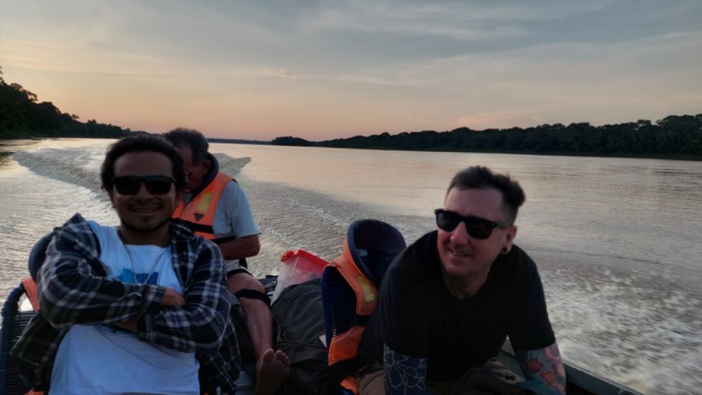 Travel planner and local crew in a motorized power boat at sunset, wearing practical casual clothing instead of safari gear.