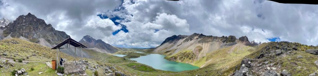 A breathtaking wide-angle panorama of the snow-capped glacial peaks and turquoise lakes of the Ausangate mountain range in the high Peruvian Andes.