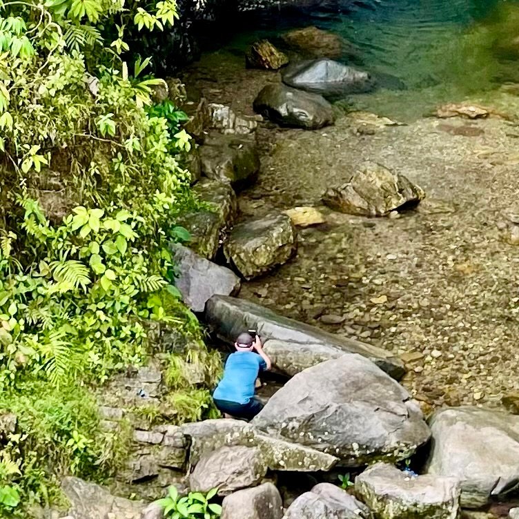 A Canadian traveler named Dave crouched among river rocks and lush jungle foliage along the 30C Interoceanic Highway in Camanti, Peru.