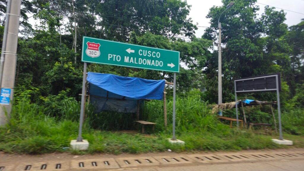 A green highway sign on the 30C Interoceanic Highway in Peru, with arrows pointing toward Cusco and Pto Maldonado.