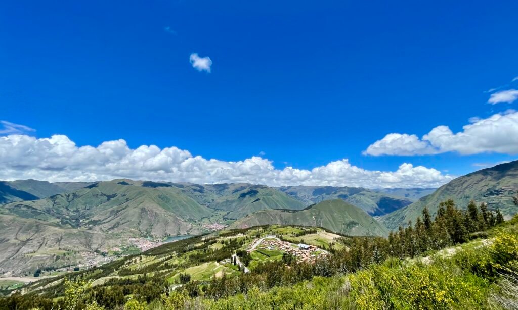 A wide landscape of the Interoceanic Highway (30C) climbing out of Cusco toward the high Andes under a clear blue sky.