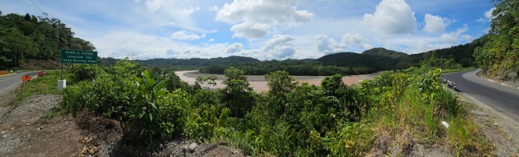 The paved Interoceanic Highway winding along a mountain ridge overlooking a river valley in the Peruvian Amazon.