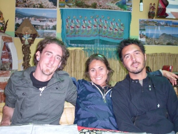 Kieran Proctor and travel companions sitting together during his first overland journey through Peru in 2007, surrounded by local Andean decor and travel posters.