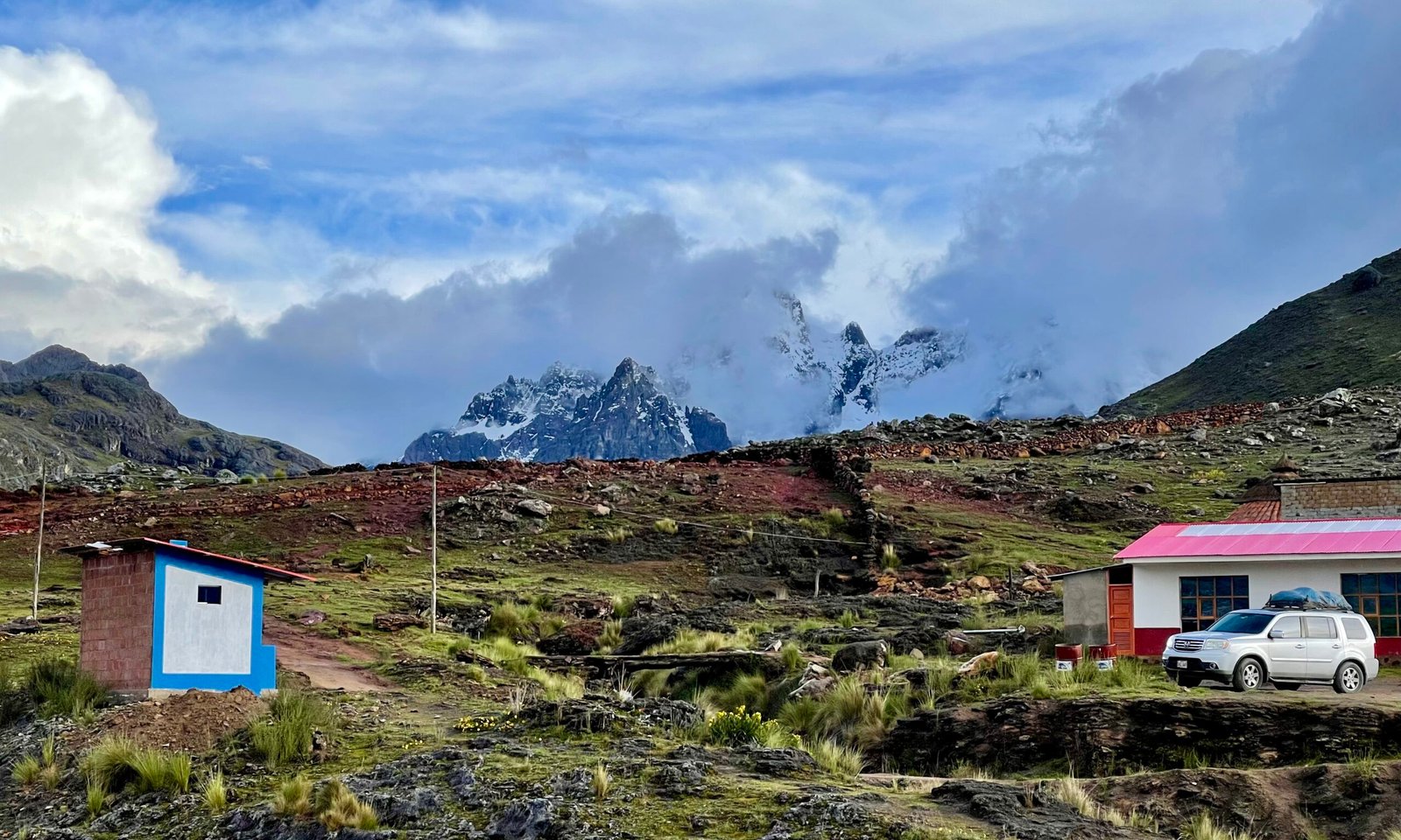 The 4,310-meter trailhead at Pacchanta village looking toward the start of the trek with the jagged peak of Ausangate looms behind heavy cloud cover.