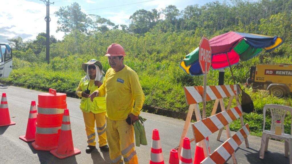 Maintenance crew and a Pare sign blocking traffic on the Interoceanic Highway due to seasonal landslides.