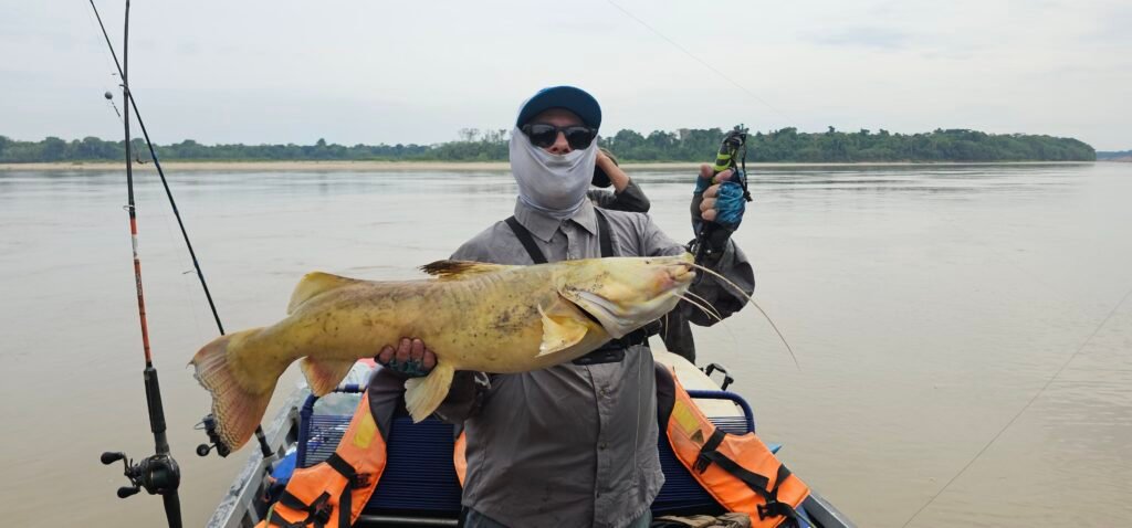 Dave holding a large catfish on a boat in the Madre de Dios river basin during the dry season.