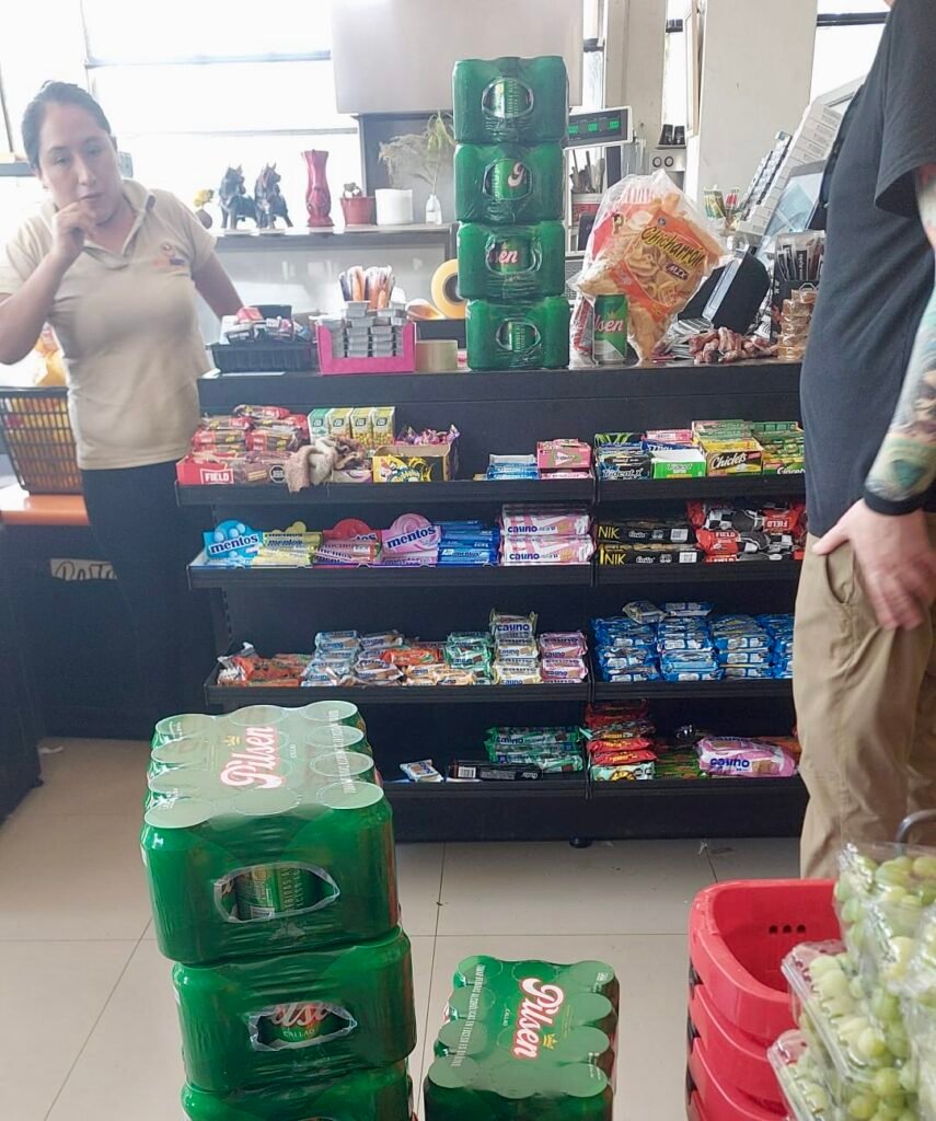 Cases of green Pilsen cans stacked for a logistical supply run in Puerto Maldonado, Peru.