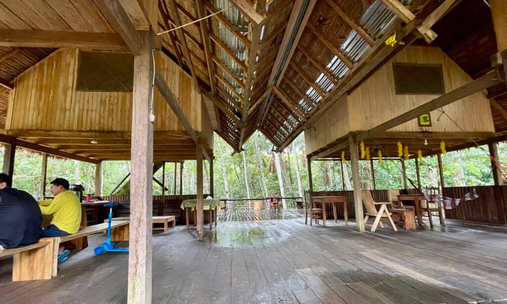 The rustic wooden common area and dining space of a jungle lodge in Tambopata, Peru.