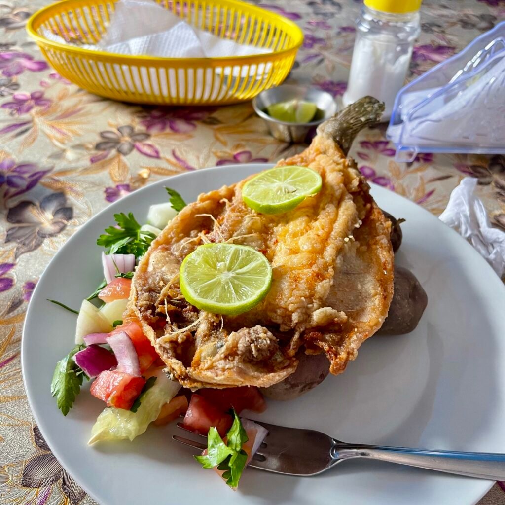 A plate of fresh, crispy fried mountain trout served with local potatoes and salad in Pacchanta, illustrating traditional Andean cuisine on the Ausangate trek.