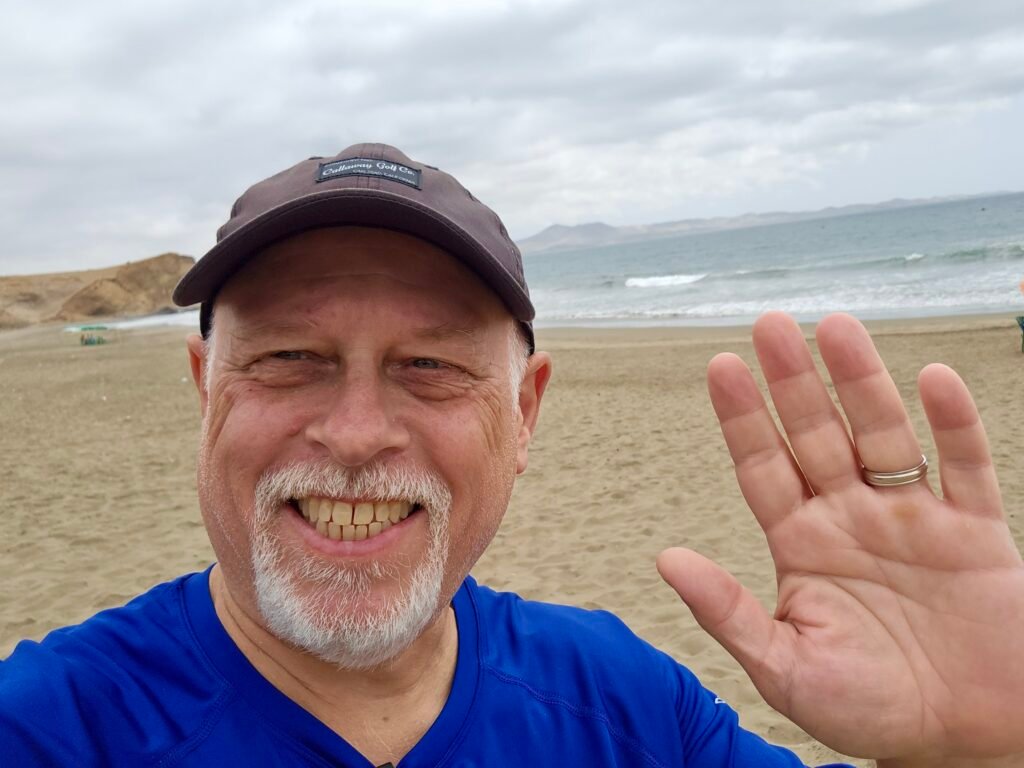 Dave smiling while waving at Playa Colorado beach in Huacho, Peru.