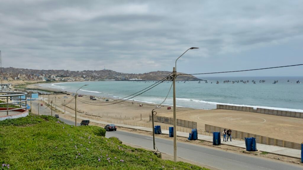 An elevated view of the main industrial city beach and port area in Huacho, Peru, showing a road and surrounding coastal town infrastructure.
