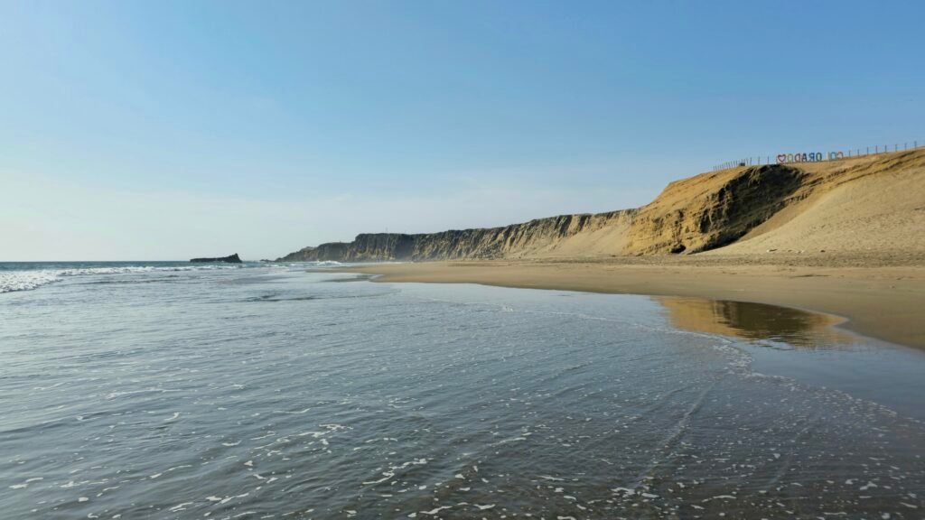 Expansive view of the sandy coastline and dramatic cliffs at Playa Colorado, part of the Eight-Beach Circuit in Huacho, Peru.