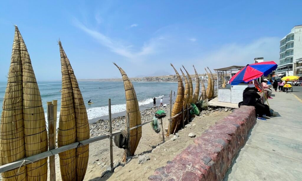 Traditional caballitos de totora reed fishing boats lined up on the sand at Huanchaco Beach in Trujillo, Peru.