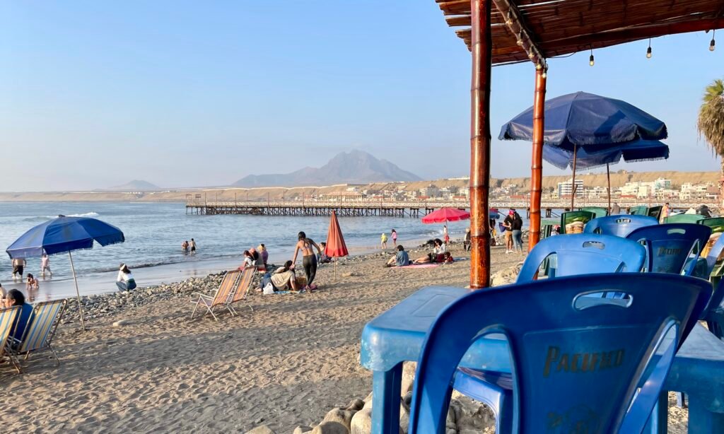 View of Huanchaco Beach and the sacred Cerro Campana mountain in the distance, seen from a beach bar in Punta Huanchaco.