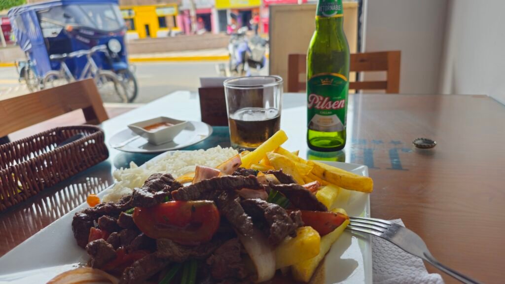 A plate of Peruvian lomo saltado served with rice and a cold beer at a local restaurant in Huarmey.