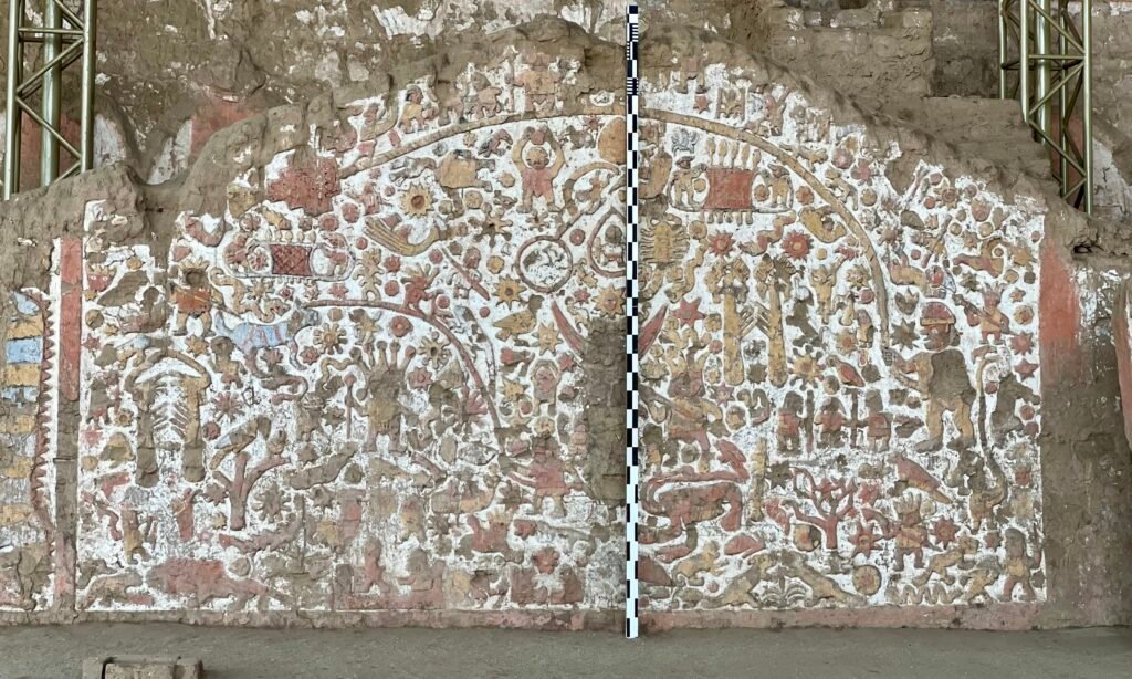 A detailed view of the complex and colorful 'Mural of the Myths' relief at Huaca de la Luna, showcasing ancient Moche iconography.