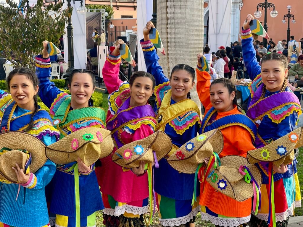 Group of six women in colorful traditional dance costumes and straw hats in Lima.