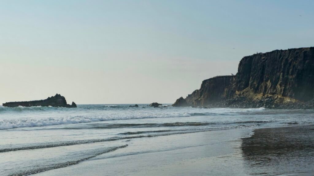 Dramatic rugged coastal cliffs and surf at Playa Colorado along Huacho's Eight-Beach Circuit.