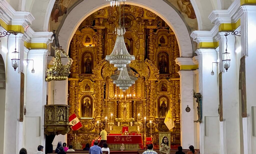 The ornate gold altar and interior chandeliers inside a colonial era Cathedral in Trujillo, Peru.